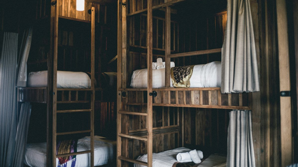 Wooden bunk beds with curtains in a large dormitory